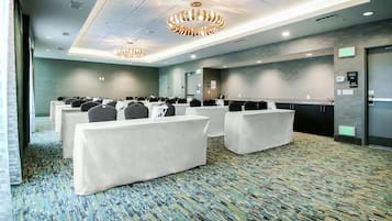 Un salón de conferencias con filas de sillas, un mostrador de recepción y una alfombra estampada.