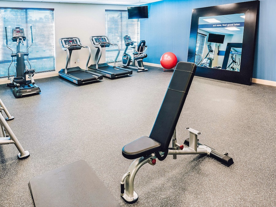 Ein Fitnessraum mit Trainingsgeräten, einer Bank und einem roten Trainingsball.