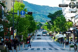 A city street with a pedestrian crossing, traffic lights, and a bus in the distance. - WORLDTRECK DINER & GUESTHOUSE - Pise - Hostel (Nagano)