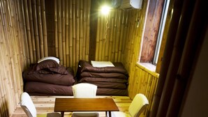 A cozy room with a wooden floor, a bed with dark bedding, a small table, and two chairs. - WORLDTRECK DINER & GUESTHOUSE - Pise - Hostel (Nagano)