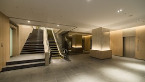 Een modern interieur met een trap, een receptiebalie en een lift.