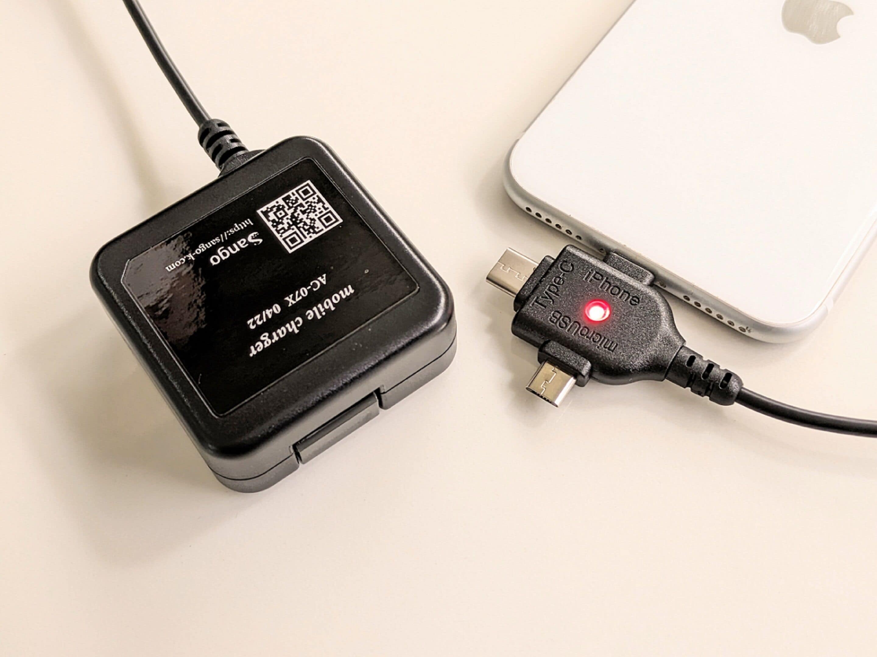Ein tragbarer Ladegerät mit einem QR-Code und einem Kabel, das an ein iPhone angeschlossen ist.