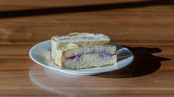 A slice of cake on a white plate on a wooden table.
