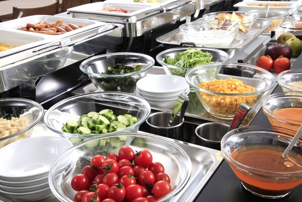 Un bufé con diversos alimentos, incluyendo tomates, pepinos y queso.