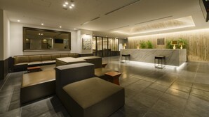 Een moderne lobby met zithoeken, een receptiebalie en een grote spiegel.