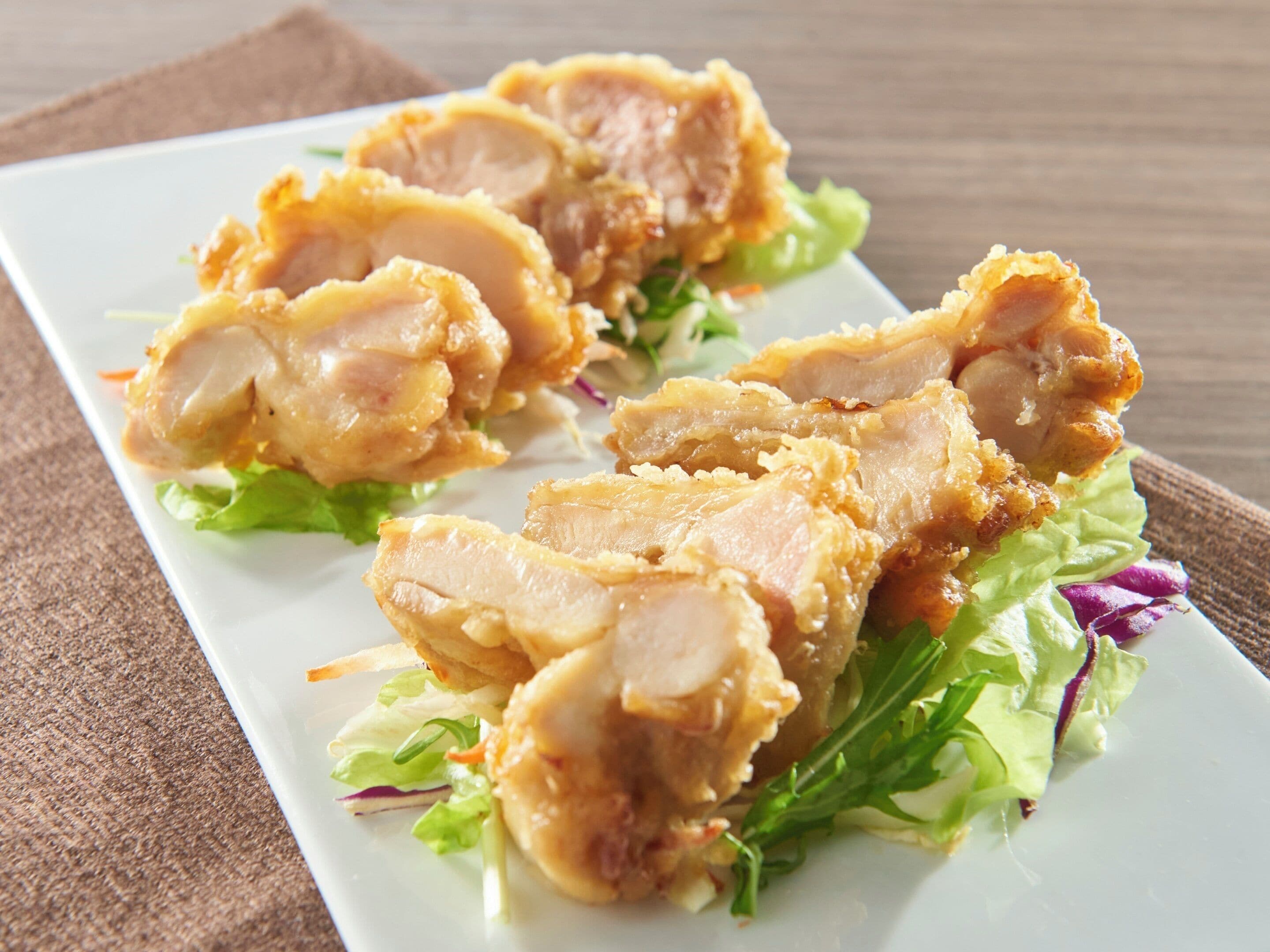 A plate of fried chicken with lettuce and a brown napkin.