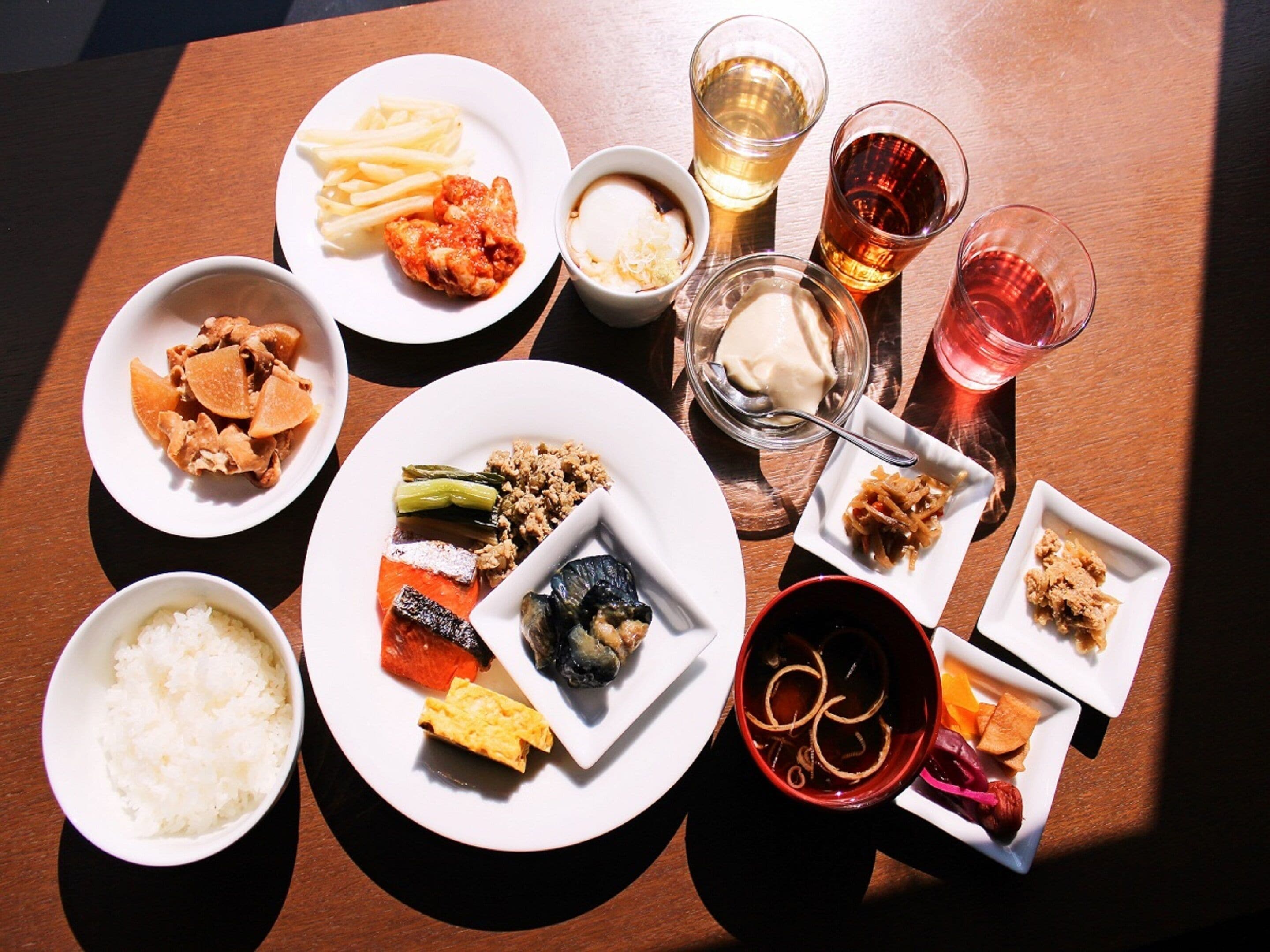 A table with various dishes, drinks, and bowls of food.