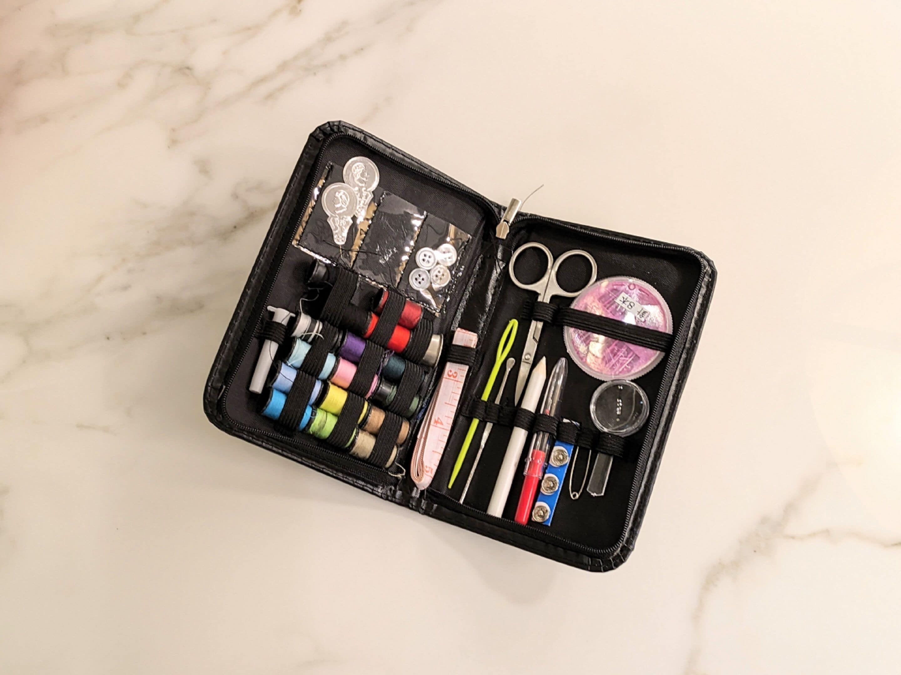 Estuche negro de maquillaje con compartimentos que contienen diversos artículos como brochas, esponjas y tubos.