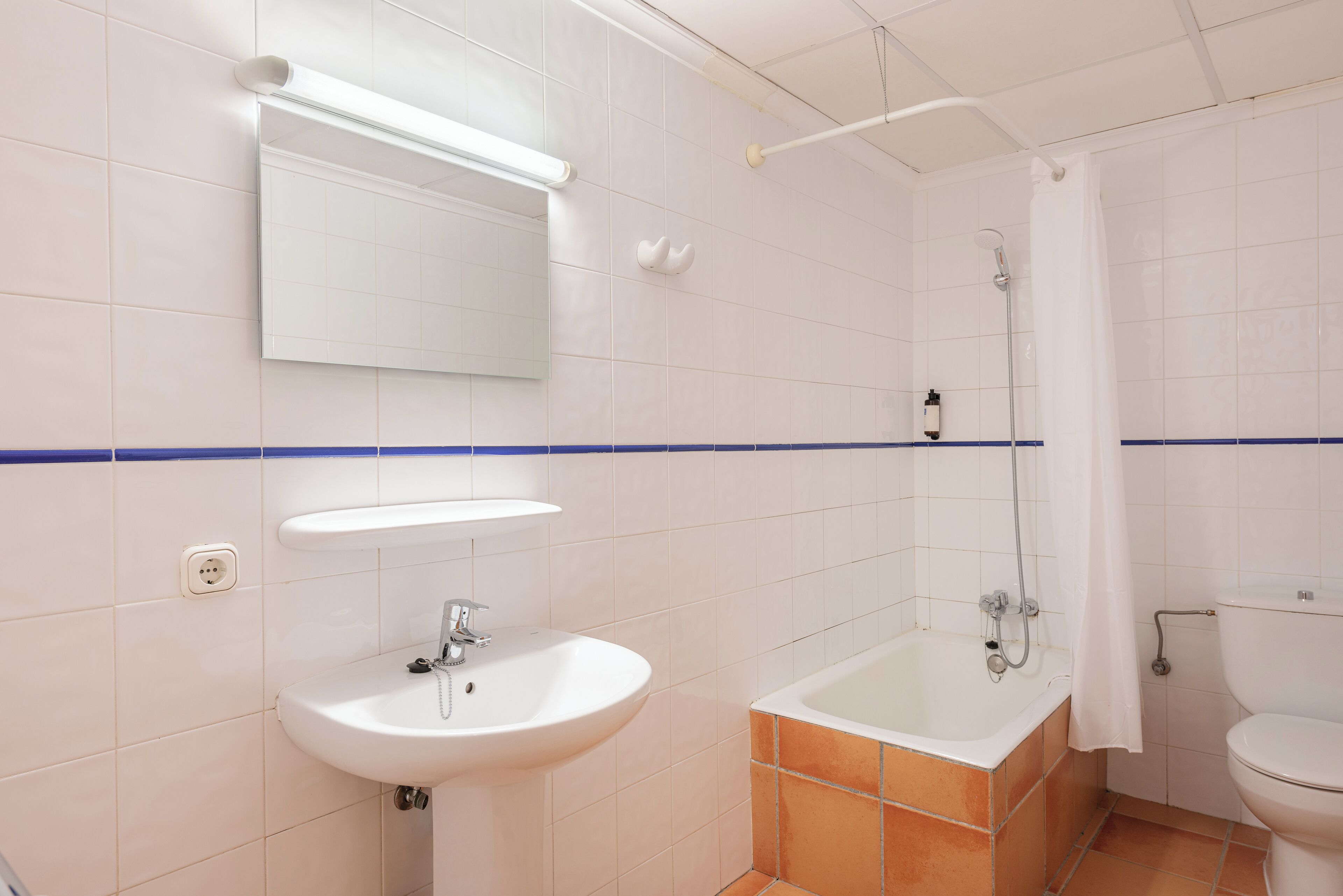 A bathroom with a white sink, a bathtub, and a toilet.