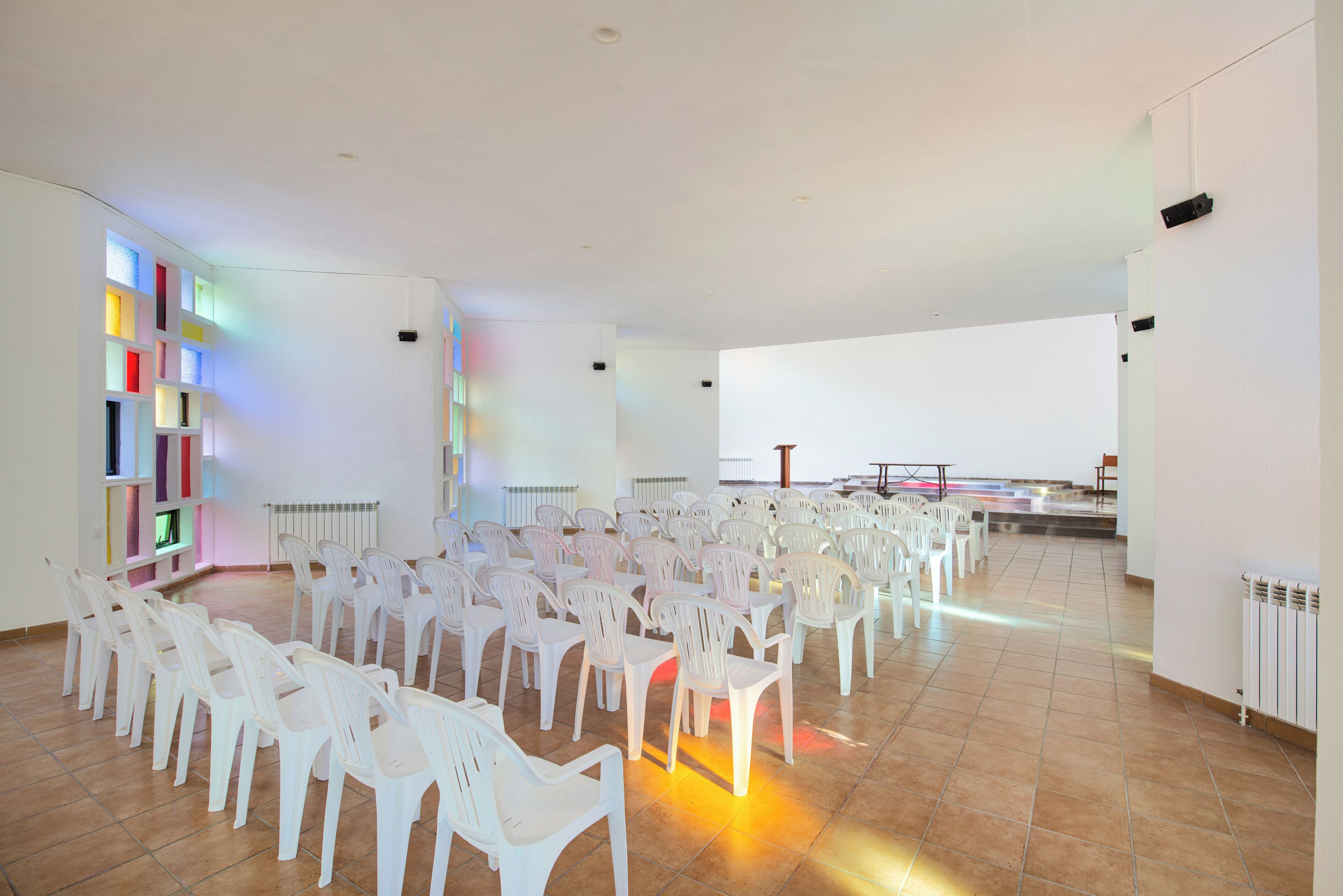 Un grand hall où sont disposées en rangées des chaises en plastique blanches, en préparation pour un événement.