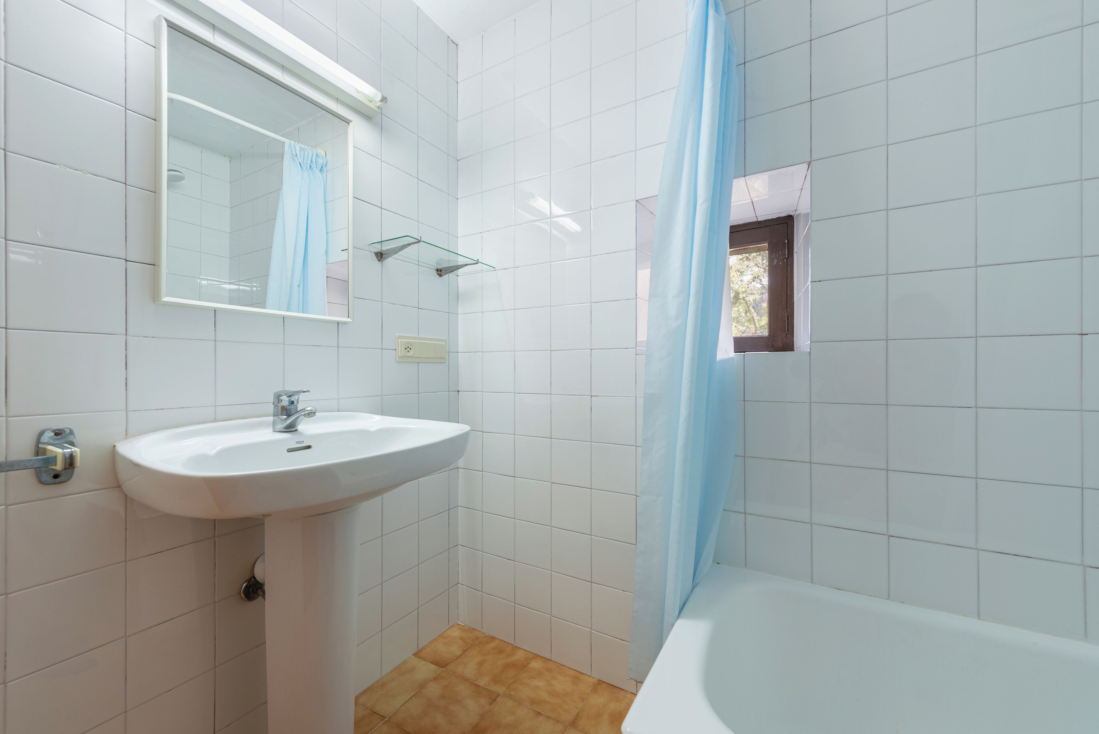 Een badkamer met een wit wastafelmeubel, een spiegel, een douche en een bad.