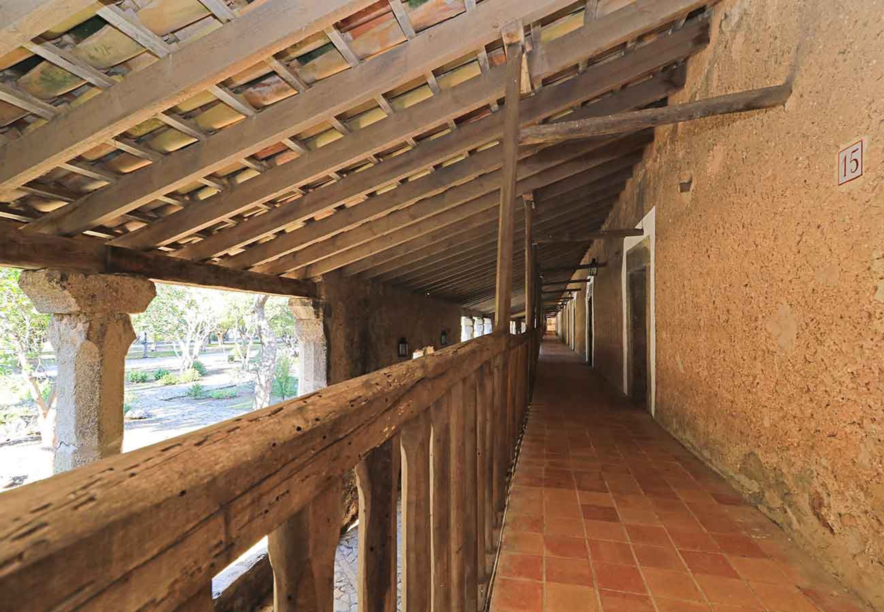 Ein Korridor mit Holzgeländer, Fliesenboden und Steinwand.