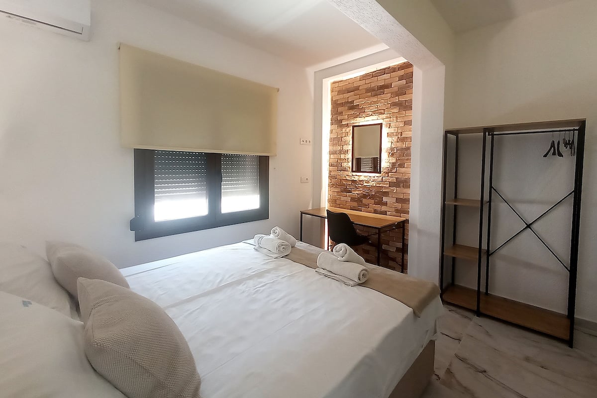 Une chambre à coucher avec un lit, un bureau, un miroir et une armoire.