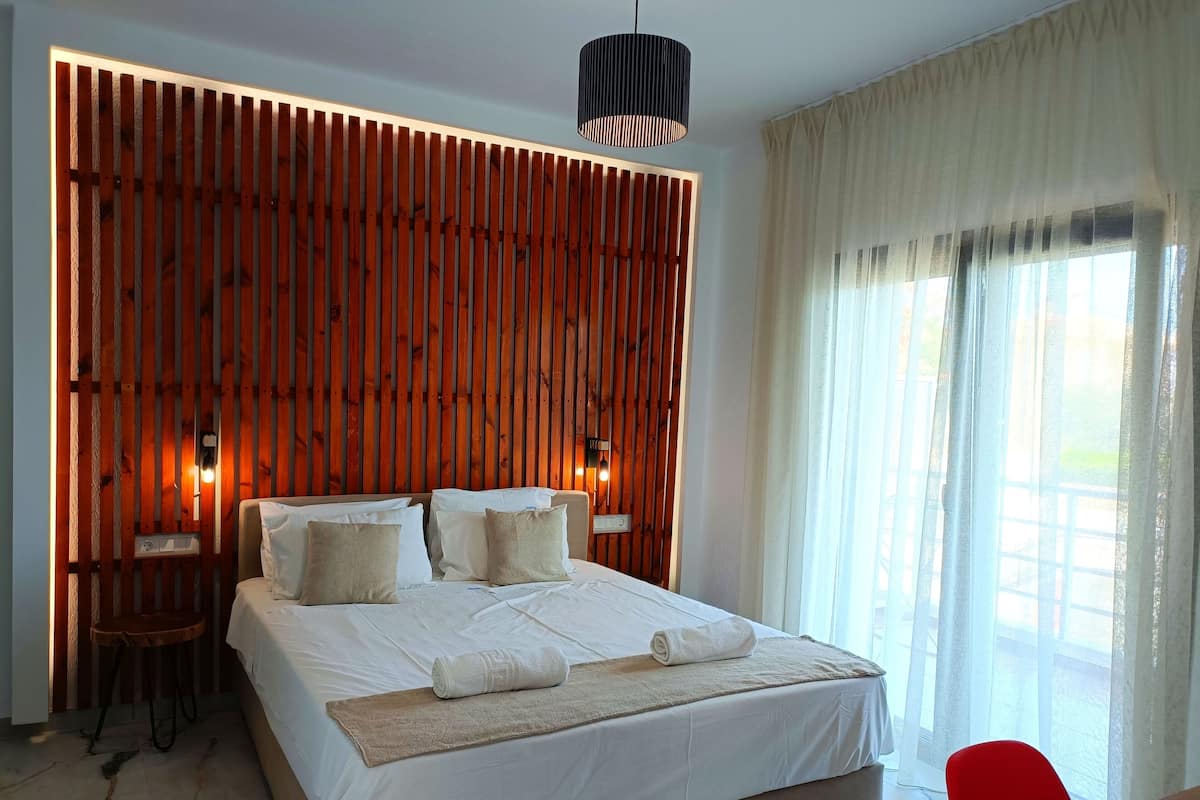 Une chambre d’hôtel moderne avec un grand lit, un mur lambrissé en bois et une vue sur l’extérieur.