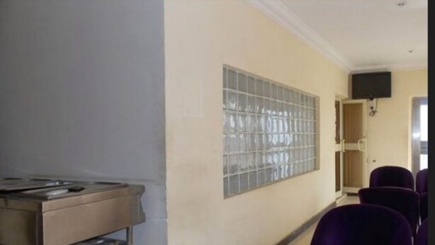 A room with a kitchenette, a large window with metal bars, and purple chairs. - Gade Place Hotel (Rumuekini)