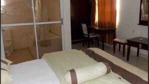 A hotel room with a bed, a desk, and a chair. - Gade Place Hotel (Rumuekini)