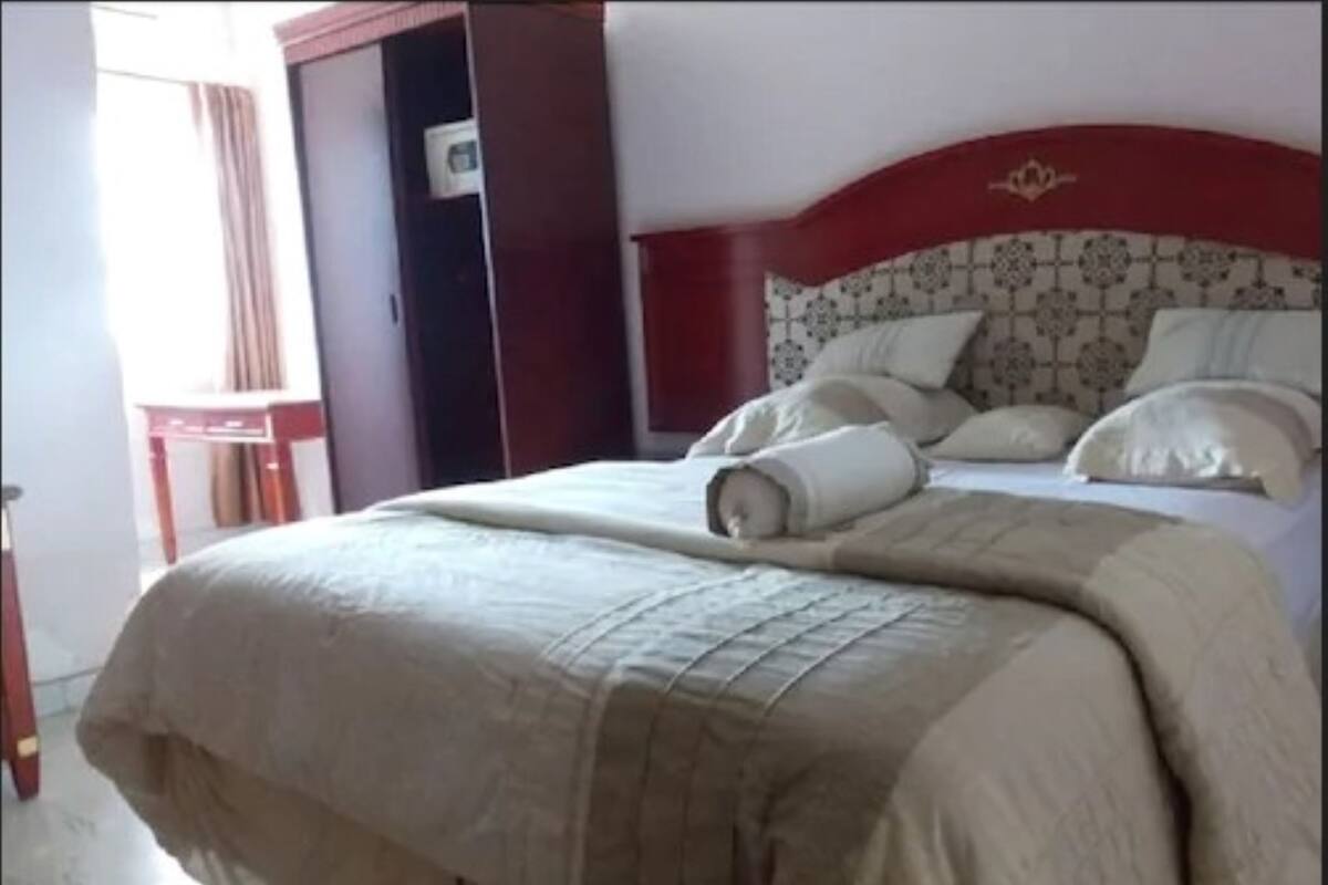Ein Hotelzimmer mit einem Bett, einem Holzkopfteil und einem Kleiderschrank.