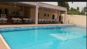 A swimming pool with a tiled edge, surrounded by a covered seating area with chairs. - Gade Place Hotel (Rumuekini)