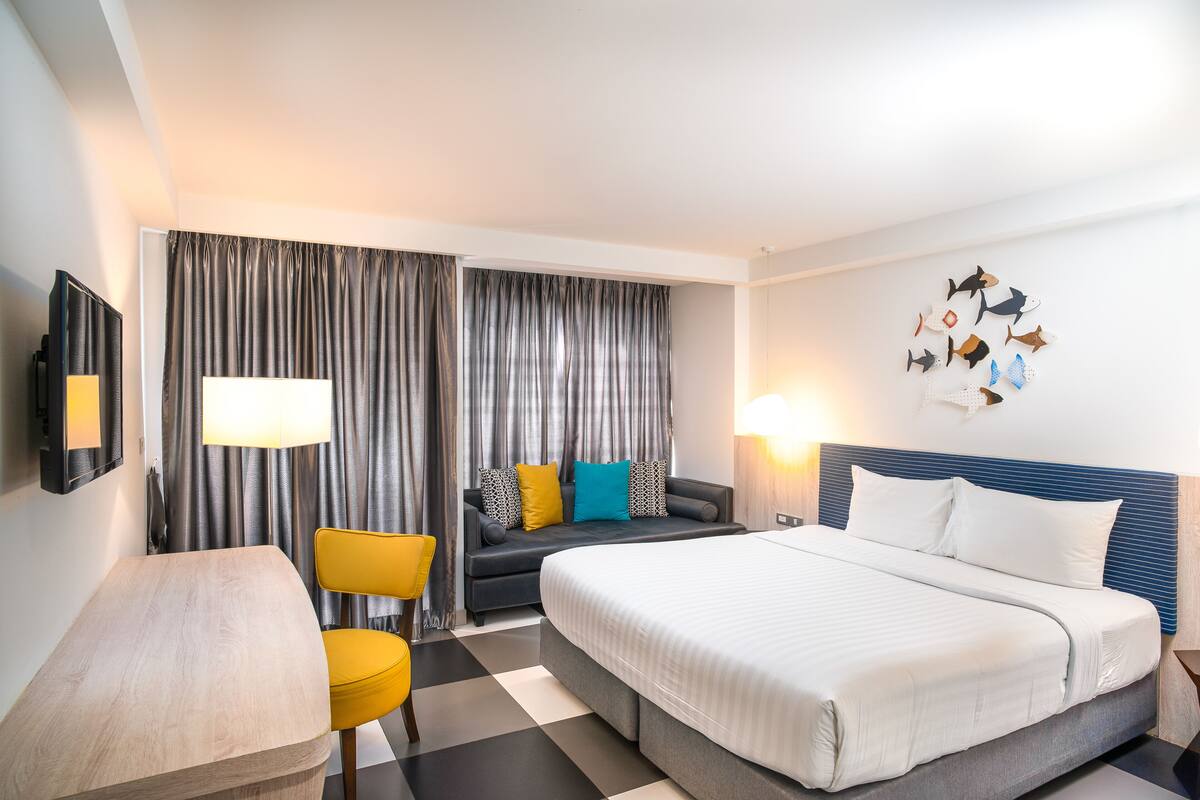 Een hotelkamer met een bed, een bank, een bureau en een stoel.