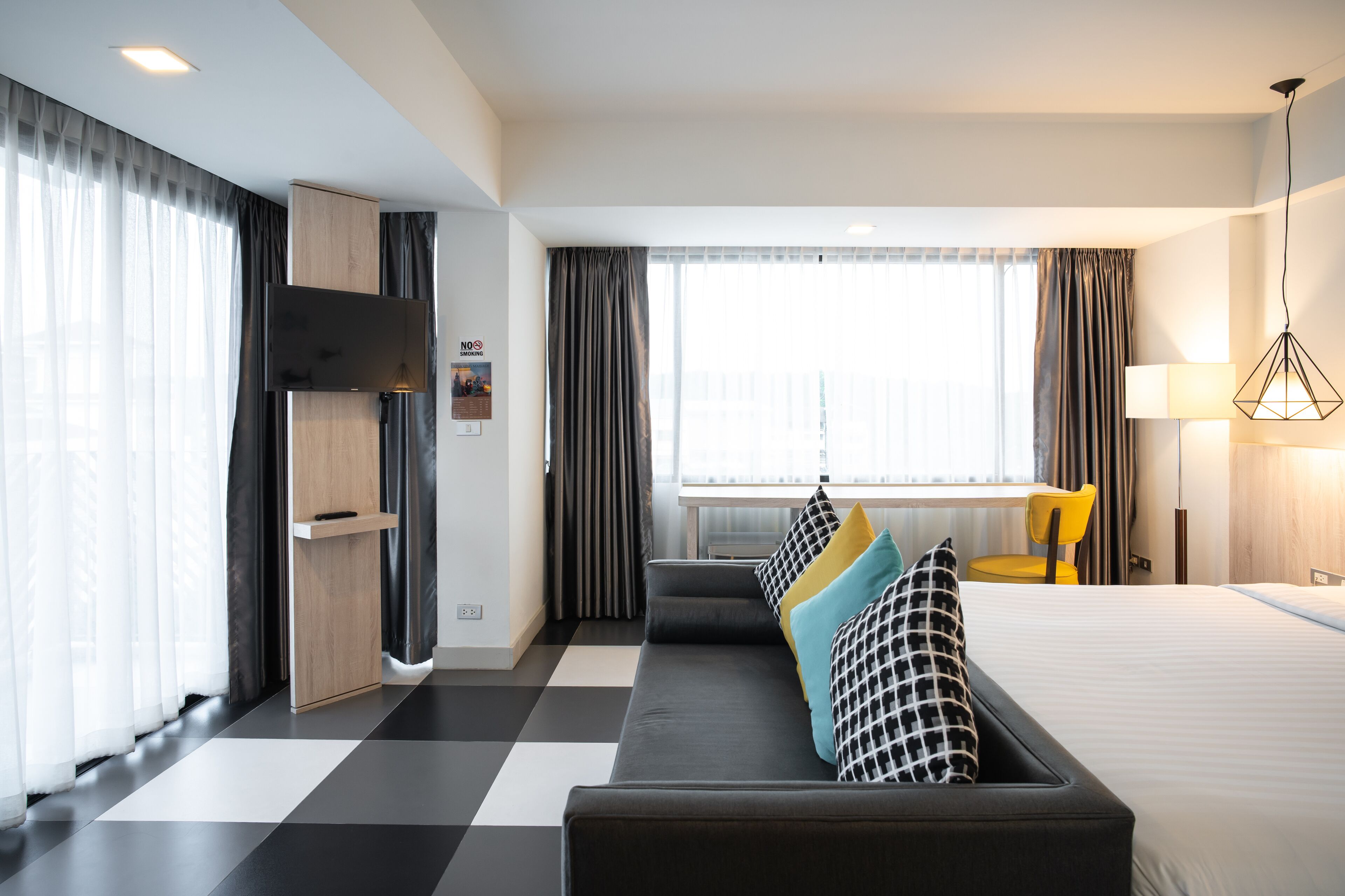 Una moderna camera d'hotel con un letto grande, un divano con cuscini decorati, una scrivania e una sedia.