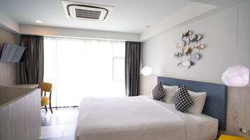 A modern hotel room with a large bed, a flat-screen TV, a desk, and a decorative fish wall art piece.