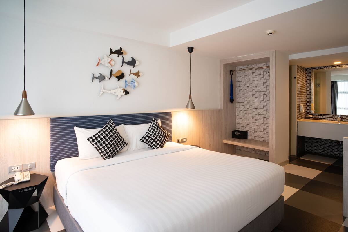 Een moderne hotelkamer met een groot bed, een visdecoratie aan de muur, een inloopdouche en een zwart-witte vloer.