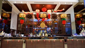 Een hotel receptie in Aziatische stijl, met een receptiebalie, decoratieve lantaarns en een bord met de tekst Siam Oriental Hotel.