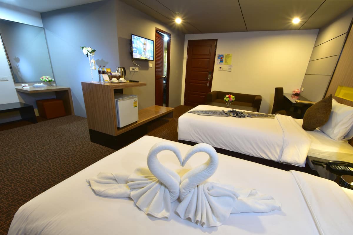 A hotel room with two beds, a desk, a television, and a minibar.