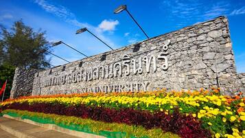 A stone wall with a university name and a colorful flower bed in front.