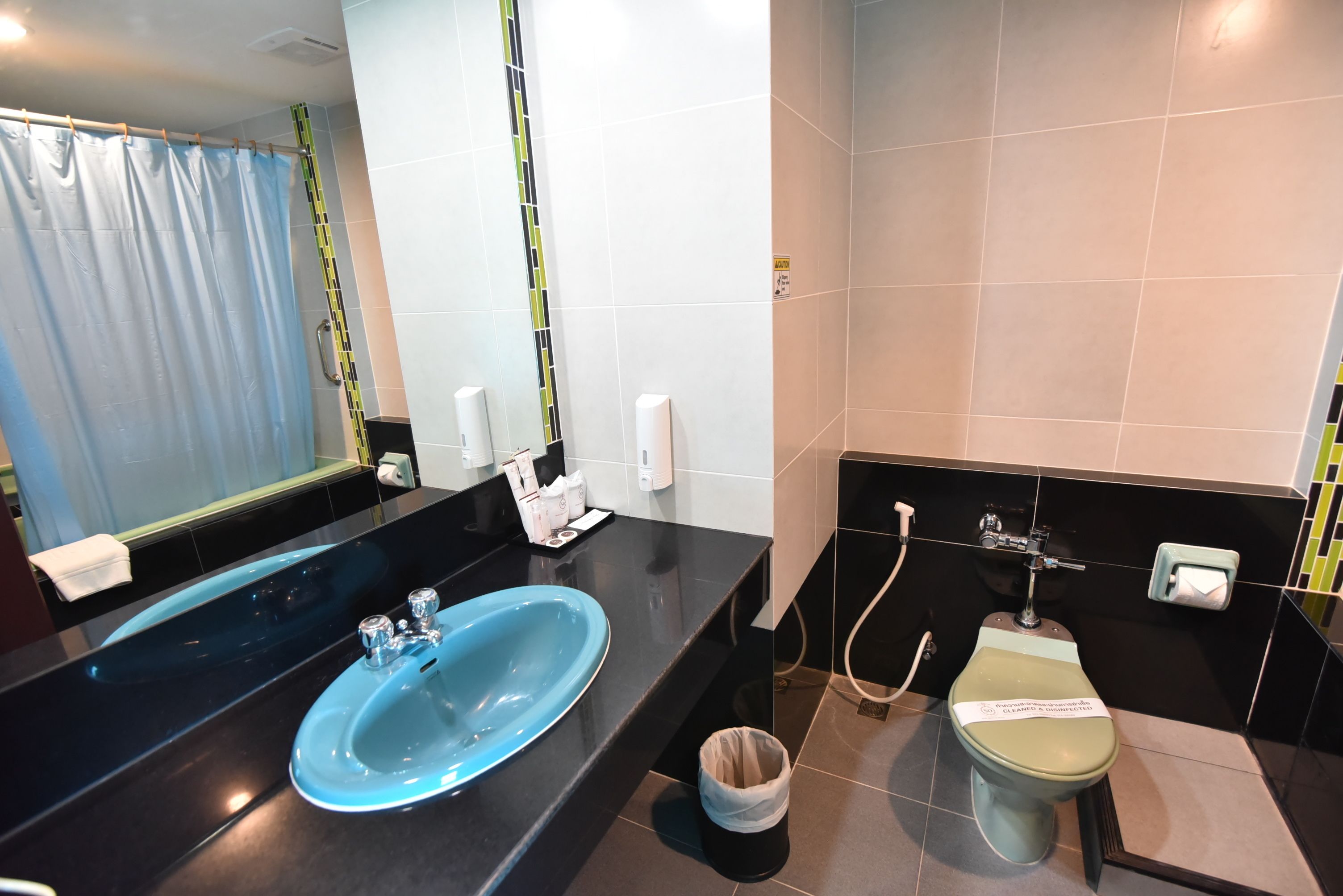 A modern bathroom with a blue sink, a toilet, and a shower.