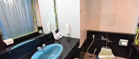 A modern bathroom with a blue sink, a toilet, and a shower.