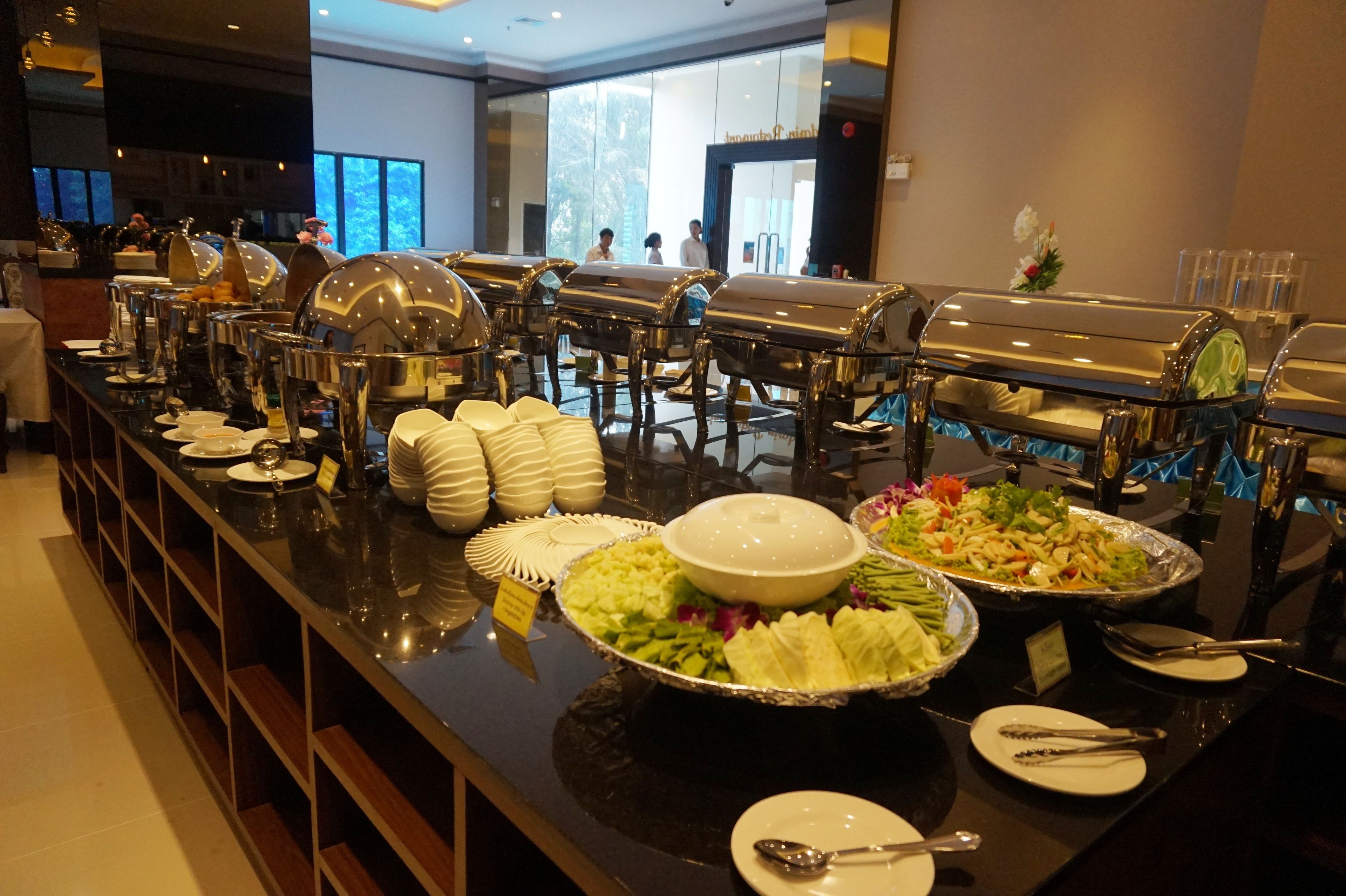 A buffet setup with various food items and serving utensils.