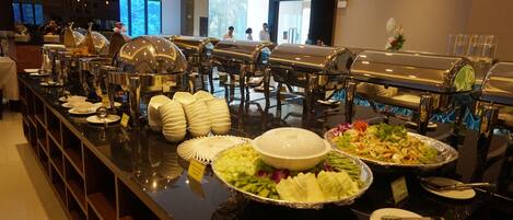 A buffet setup with various food items and serving utensils.