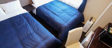 A hotel room with two beds, a desk, and a chair.