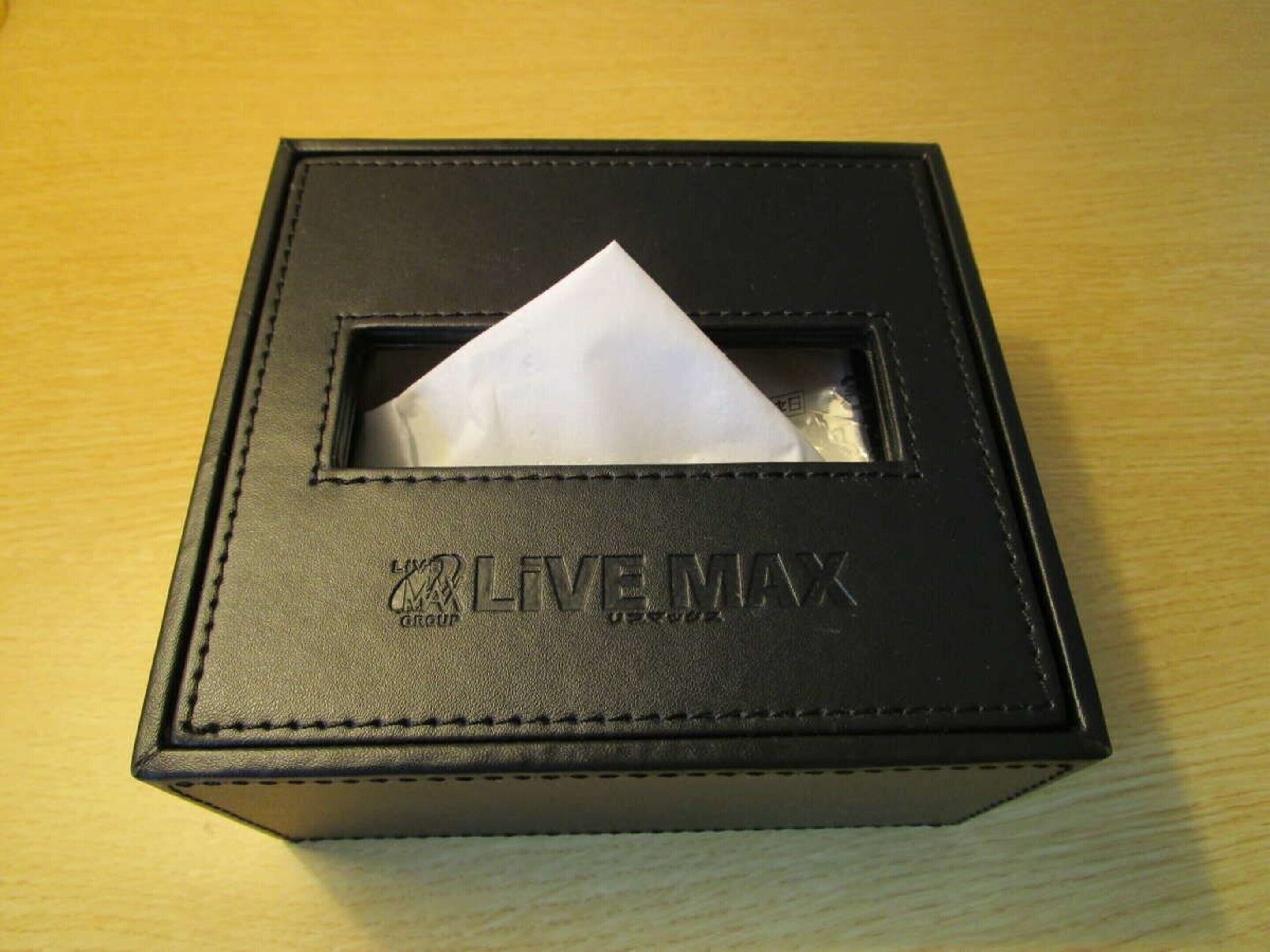 A black leather box with a white tissue inside, labeled "LIVE MAX".