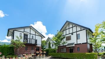 Een rij moderne gebouwen met twee verdiepingen en een symmetrische gevel, met een combinatie van wit en donkerbruin, en een verzorgde tuin met potplanten en bloemen.