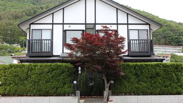 Un immeuble à deux étages, doté d’une façade symétrique, de grandes fenêtres et d’un balcon à chaque étage.