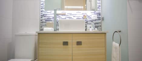 Un baño con inodoro, lavamanos con espejo y toallero.