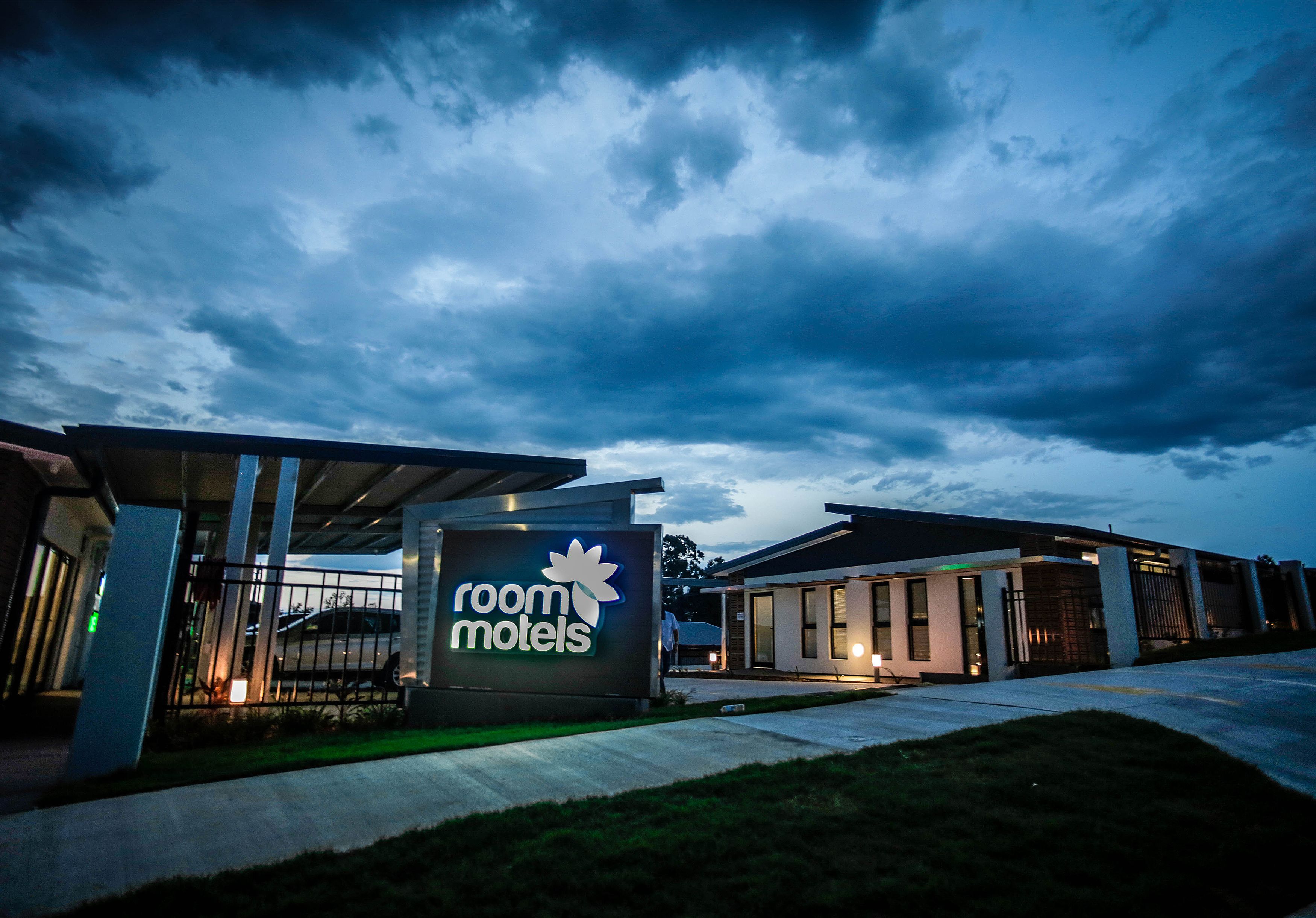 A modern motel with a prominent sign, a covered parking area, and a well-lit entrance.