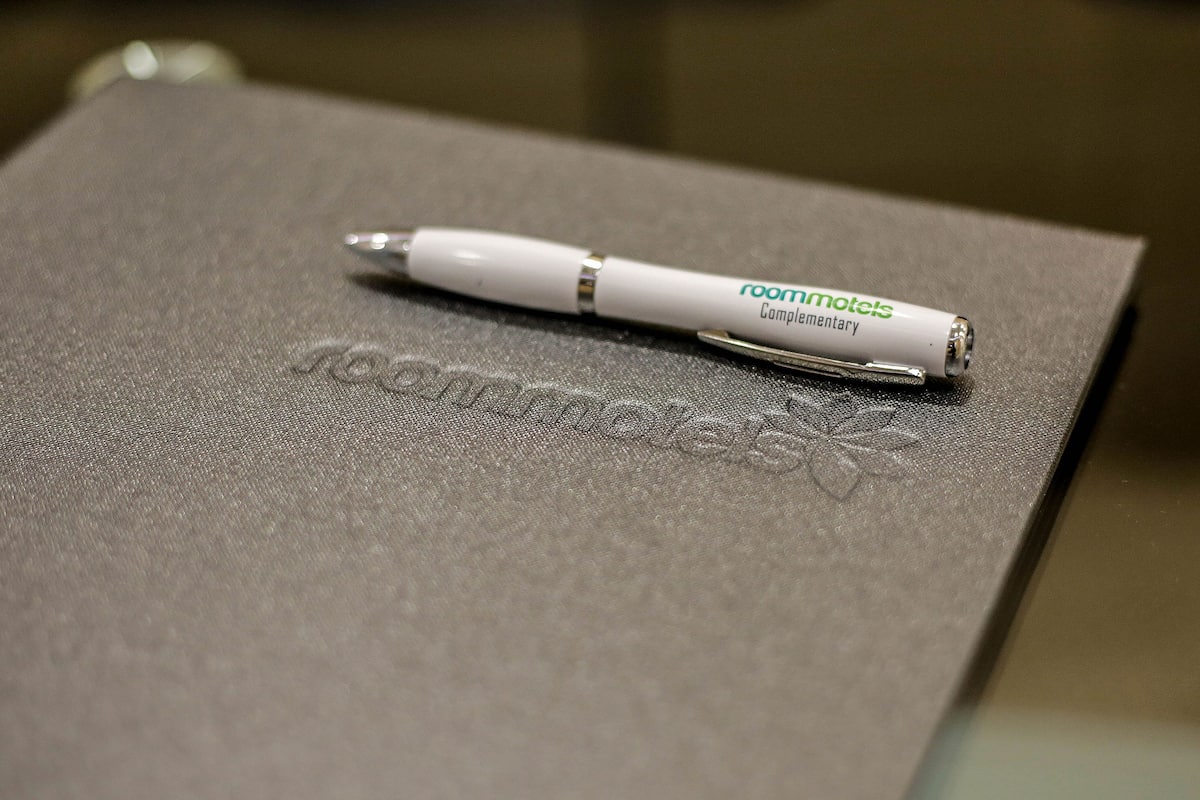 A white pen with "roommotel" and "complementary" text on a textured surface.