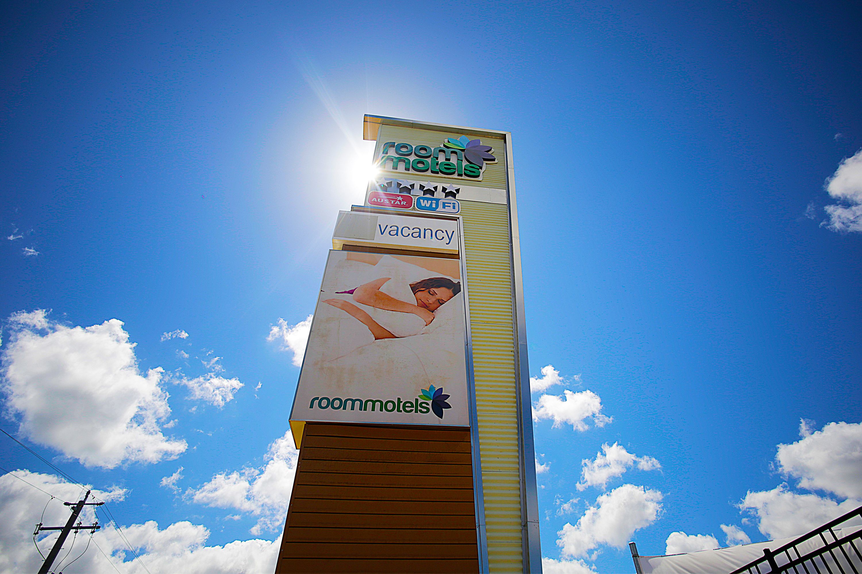 A tall sign for RoomMotel with a vacancy advertisement.