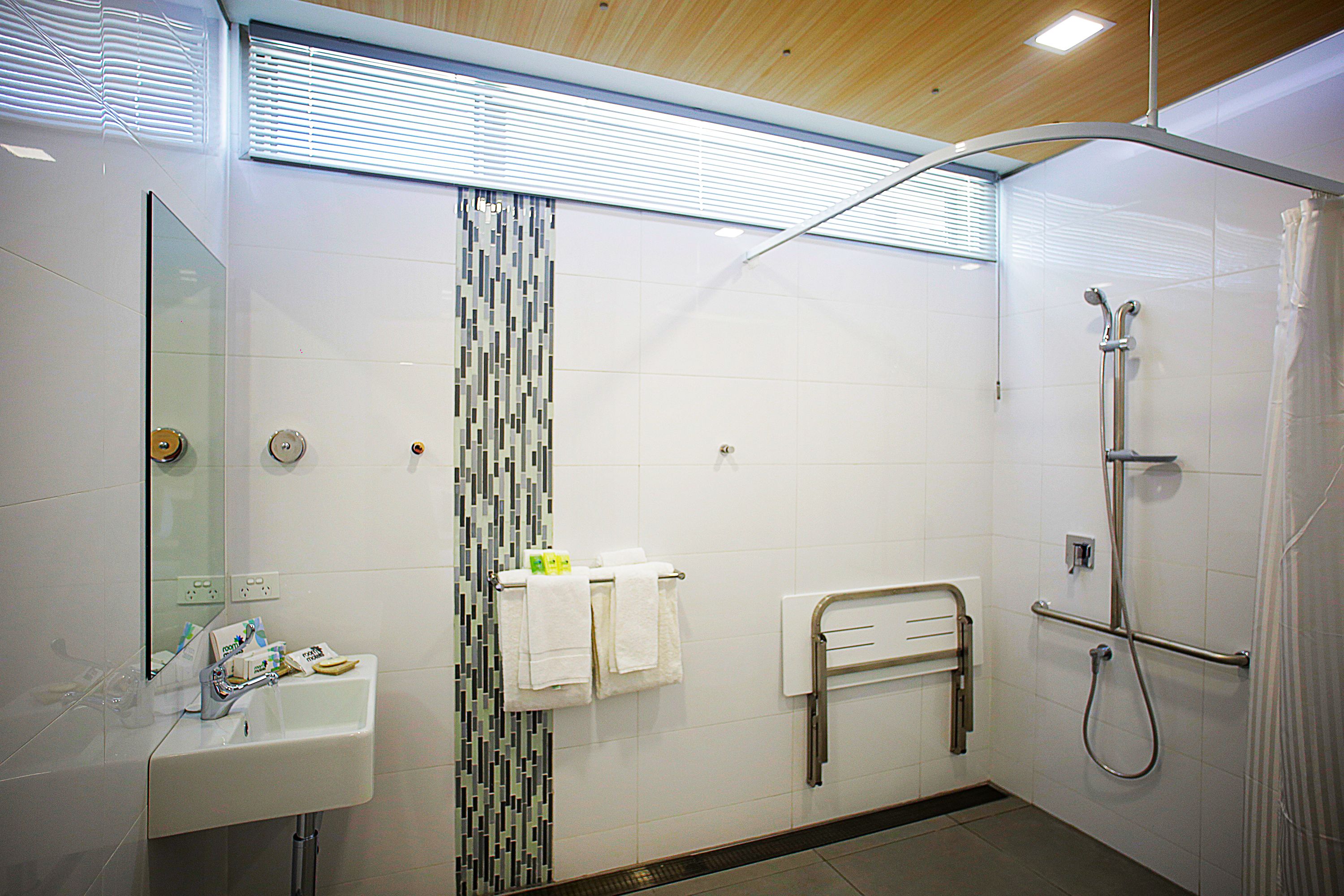 A modern bathroom with a sink, mirror, shower, and towel rack.