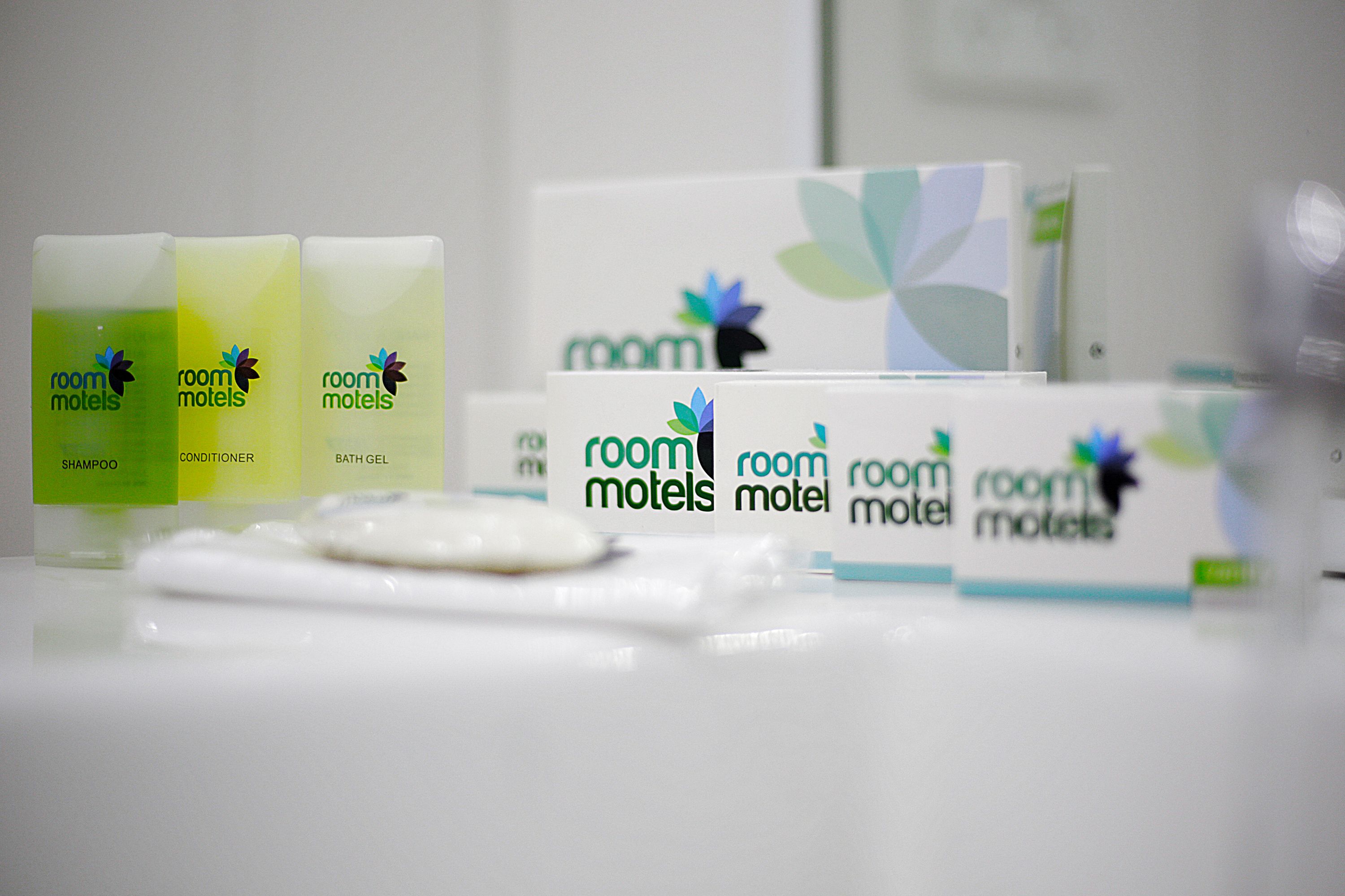 Ein Badezimmer-Waschtisch mit Toilettenartikeln, darunter Shampoo, Conditioner und Duschgel von Room Moteis.
