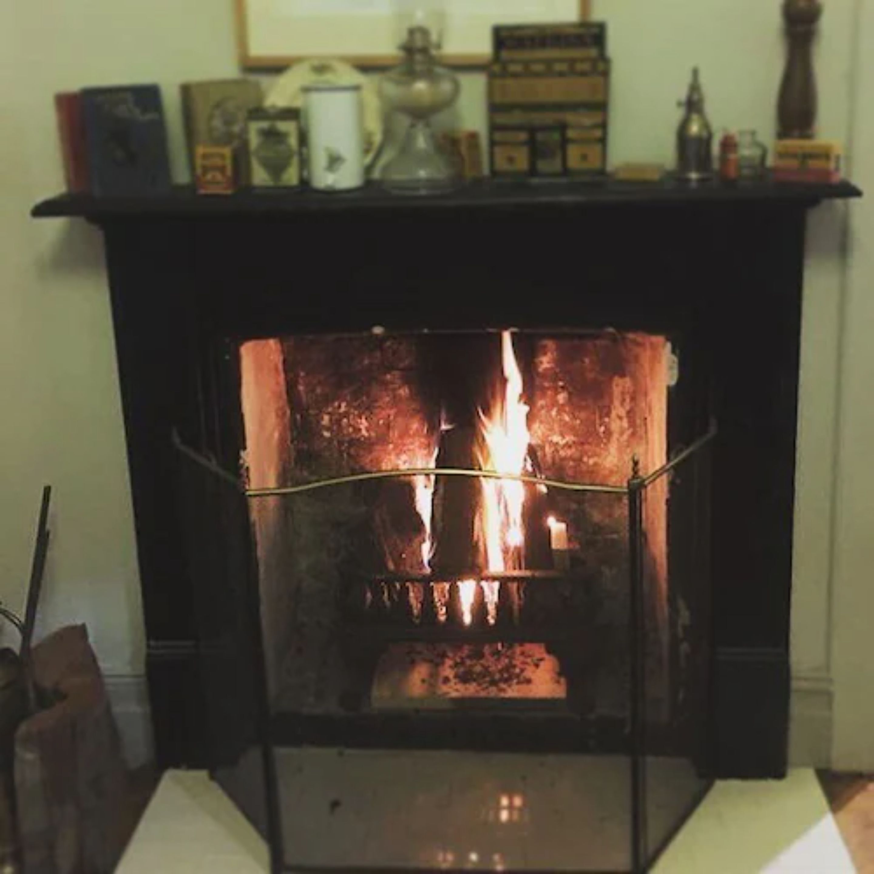Una chimenea con fuego encendido, rodeada por una repisa con varios objetos.