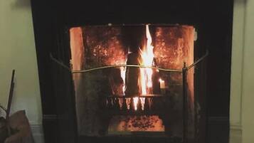 Una chimenea con fuego encendido, rodeada por una repisa con varios objetos.