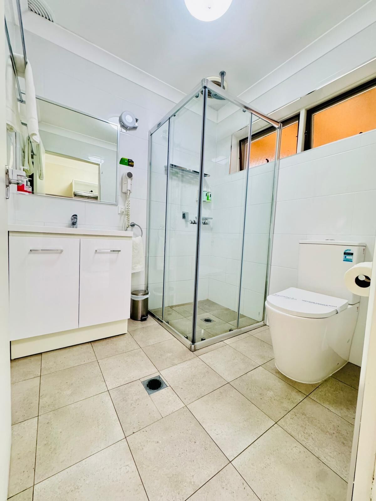 Un bagno moderno con cabina doccia in vetro, un water e un lavandino con specchio.