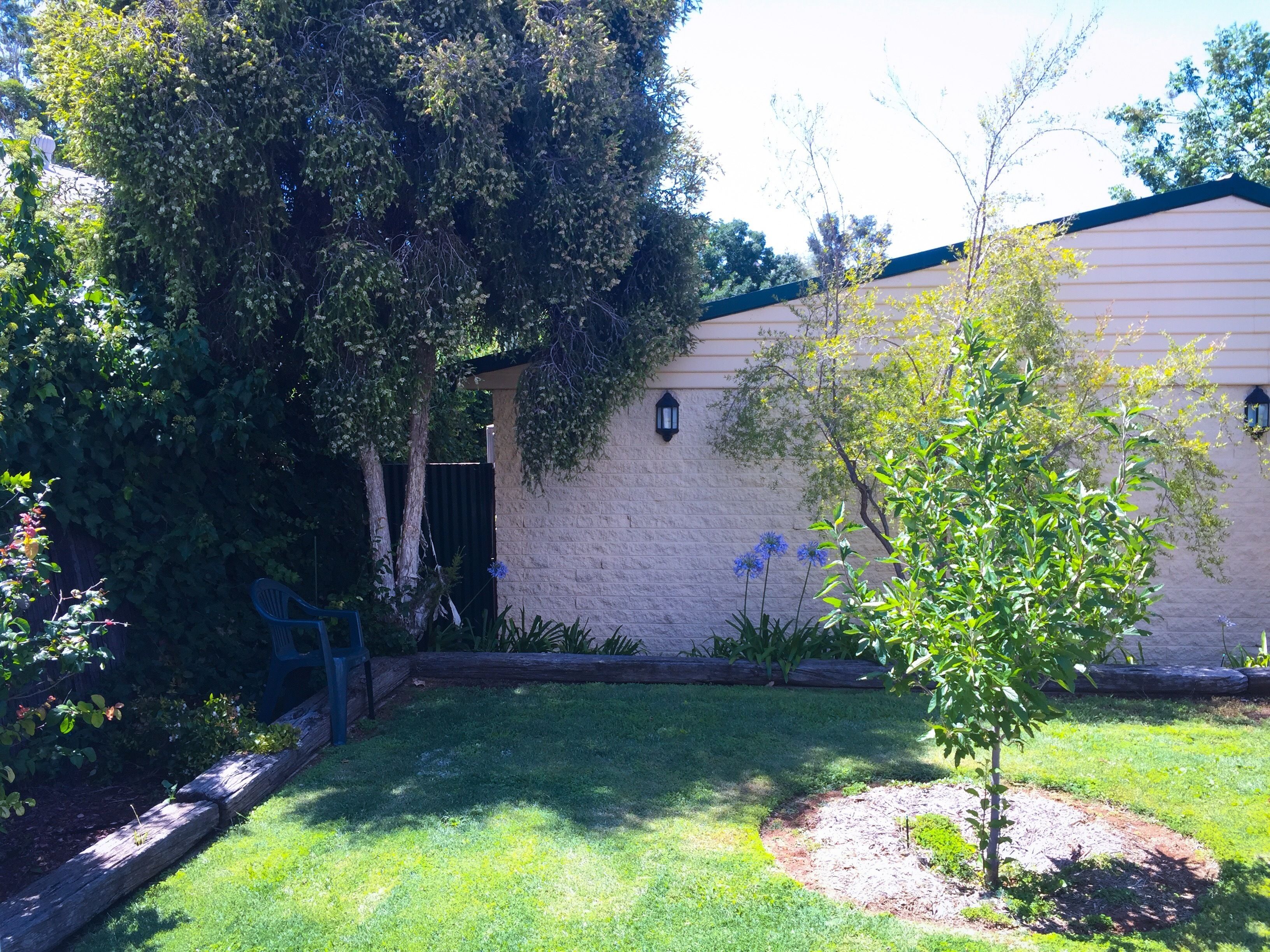 A residential property with a well-maintained lawn, a small tree, and a building with a light-colored exterior and a dark roof.
