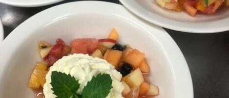 Trois bols de salade de fruits, garnis de crème fouettée et de feuilles de menthe.