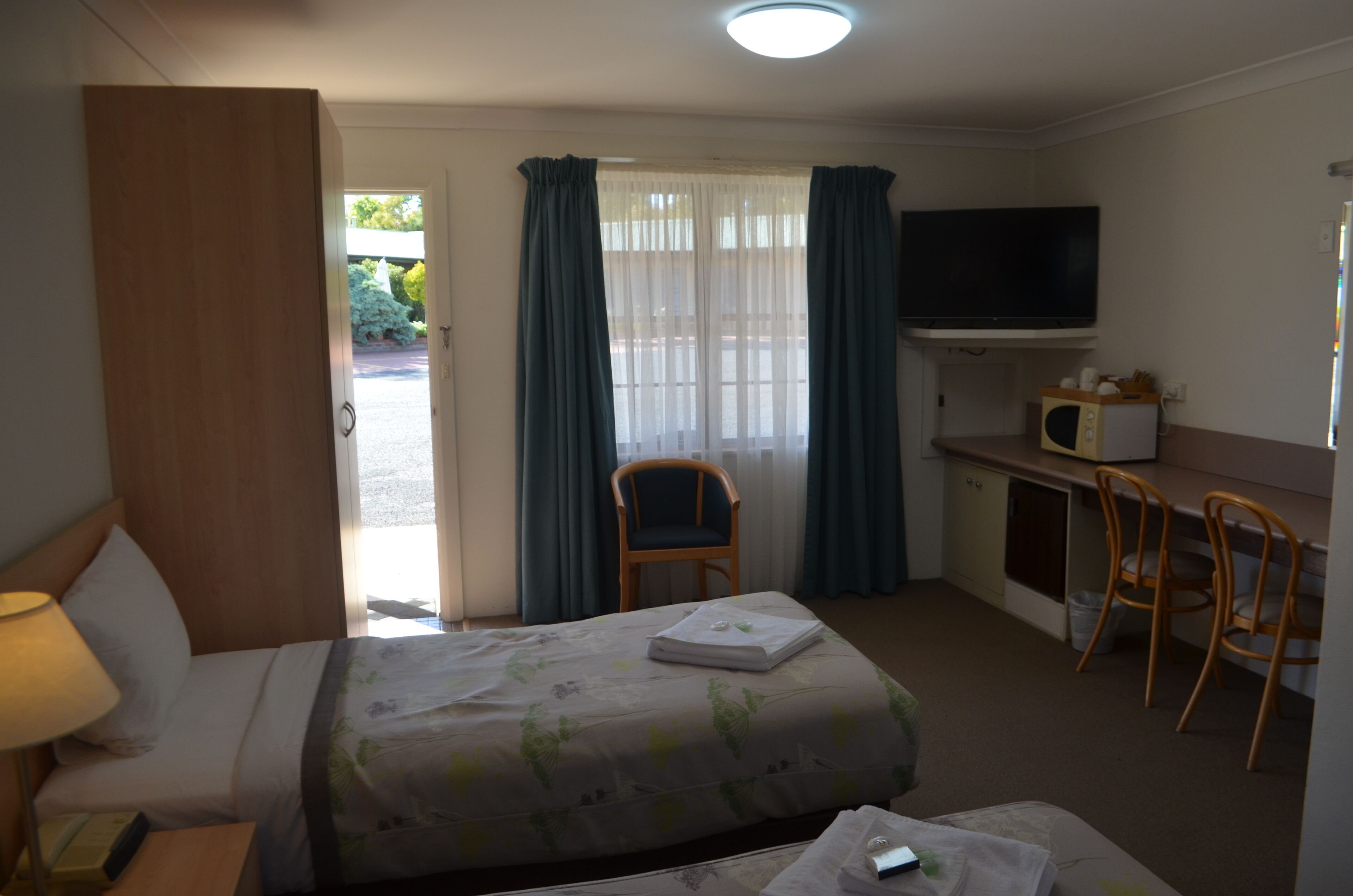Una habitación de hotel con una cama, un escritorio, un televisor y una silla.