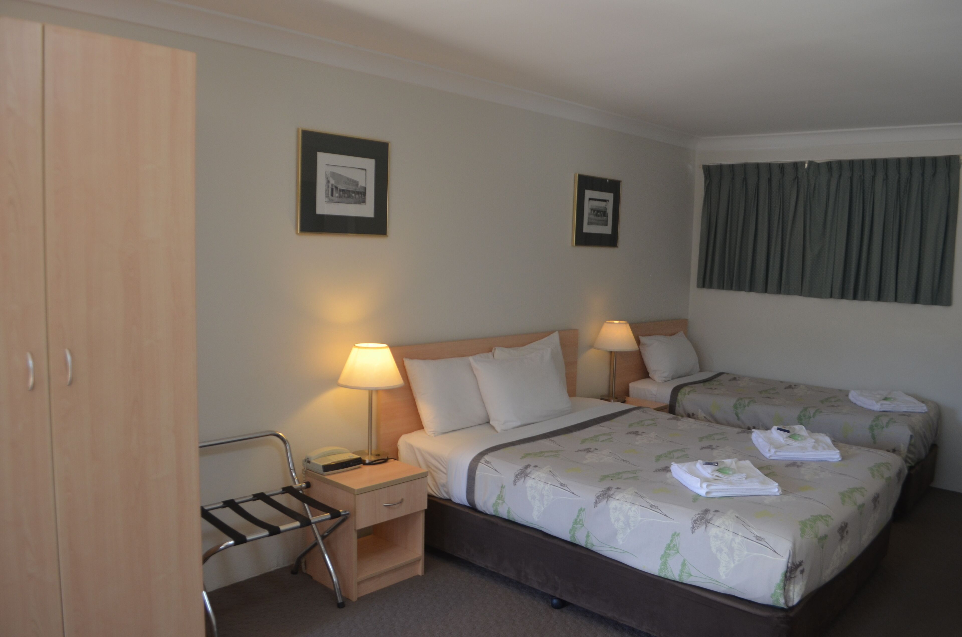 A hotel room with a bed, two bedside tables, a desk, a chair, and a wardrobe.
